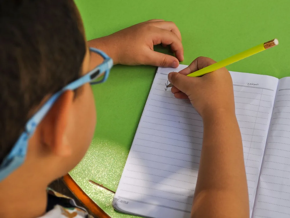 Niño con gafas haciendo tareas durante el tratamiento del ojo vago