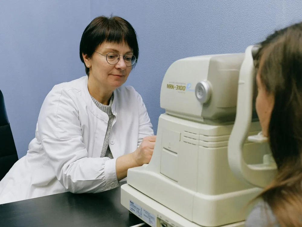 Especialista realizando un examen de la visión a una paciente en consulta de uveítis